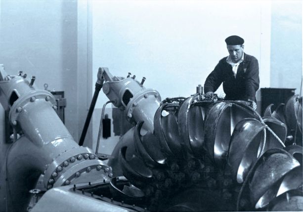 En arbeider reparerer en turbin i et vannkraftverk