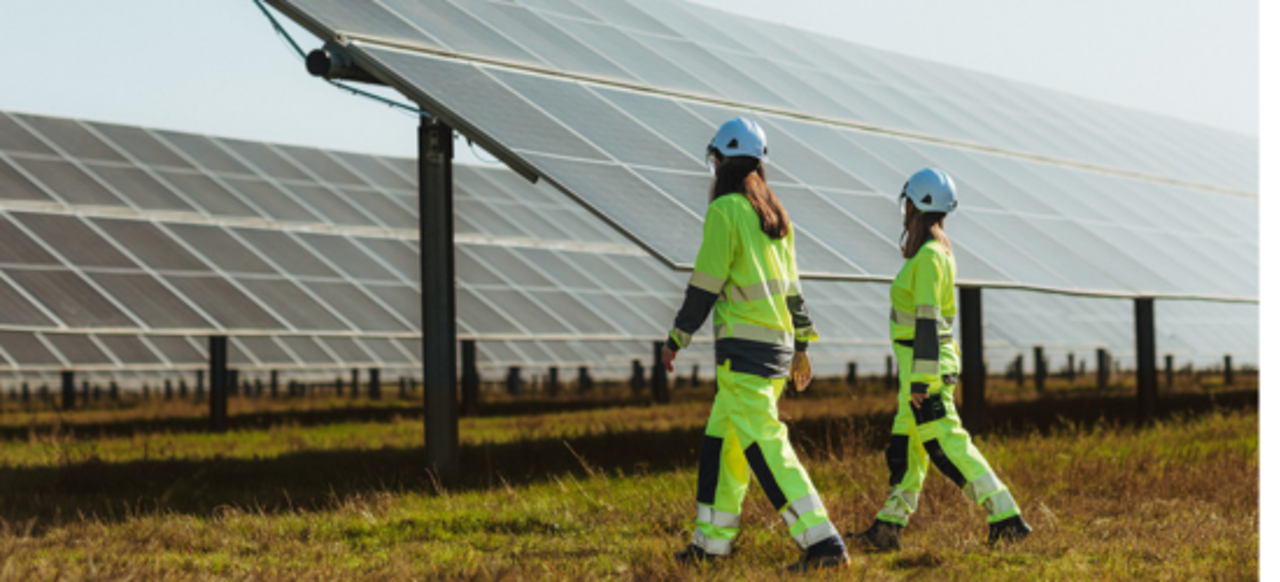 To ansatte går langs solcellepanel
