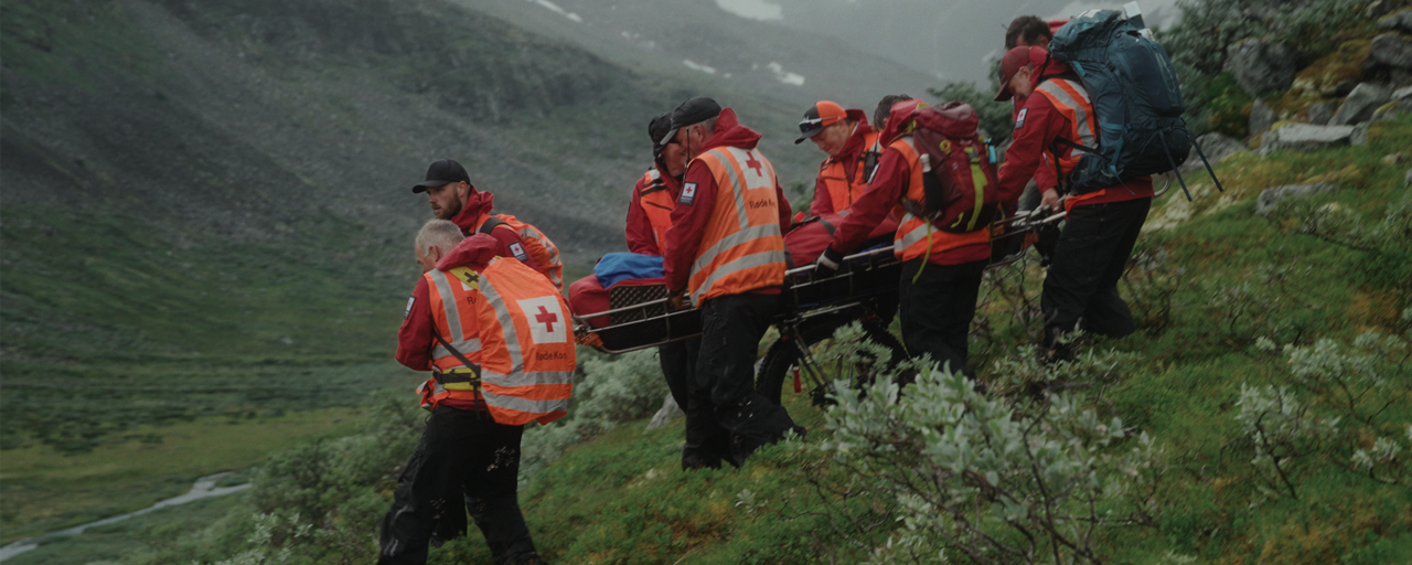 En gruppe mennesker står og snakker sammen i fjellandskap