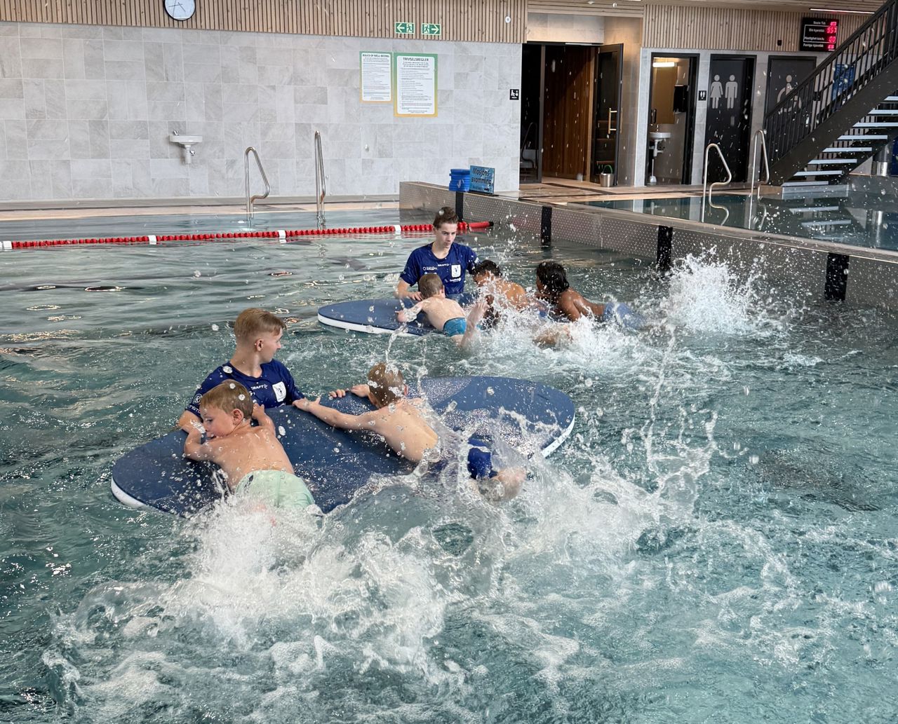 Barn som svømmer i en svømmehall