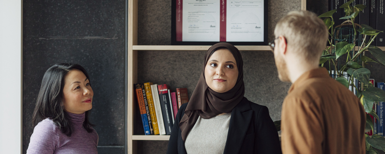 Tre ansatte i i kontorlanskap snakker