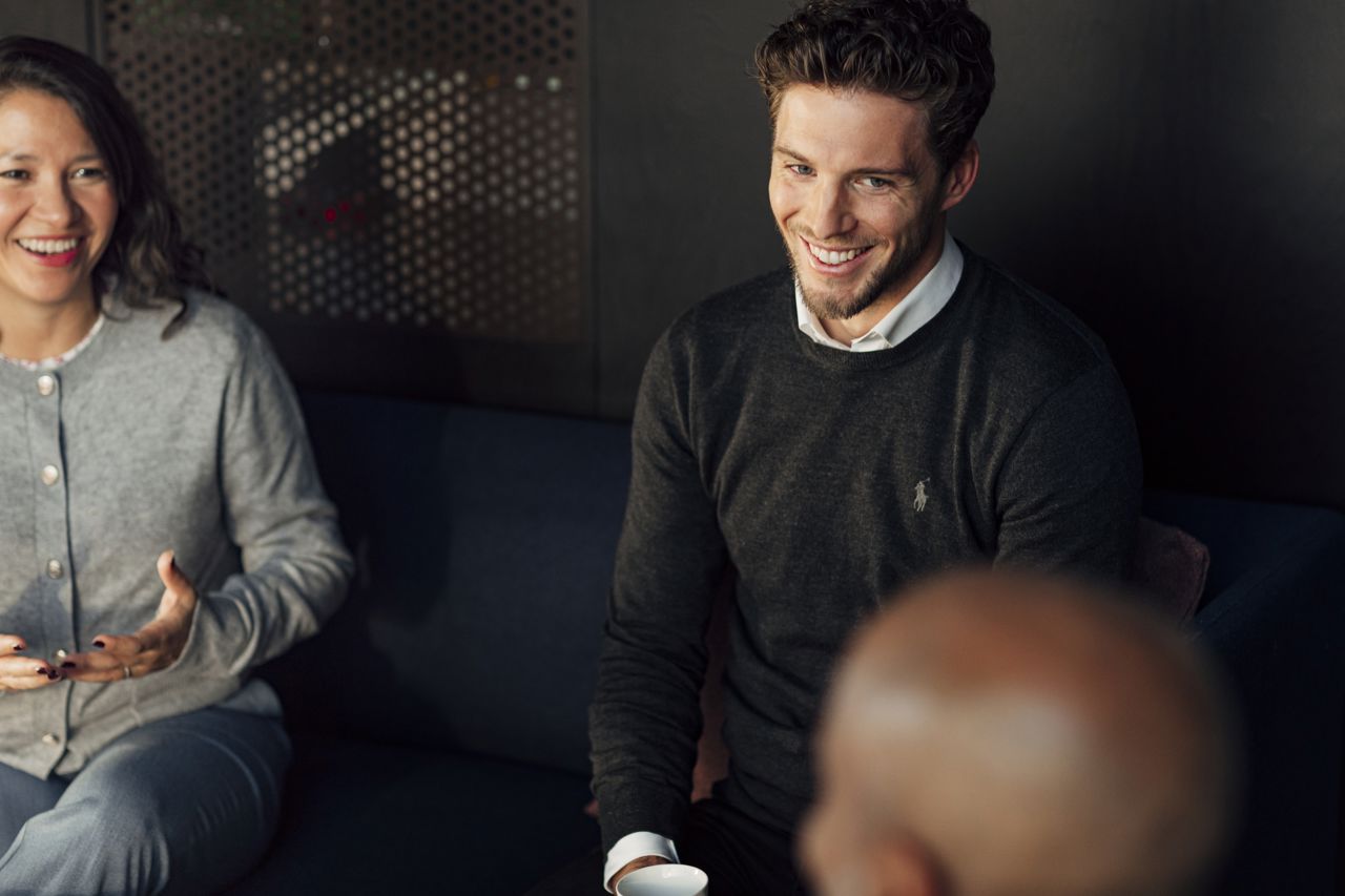 Tre ansatte snakker sammen og ler