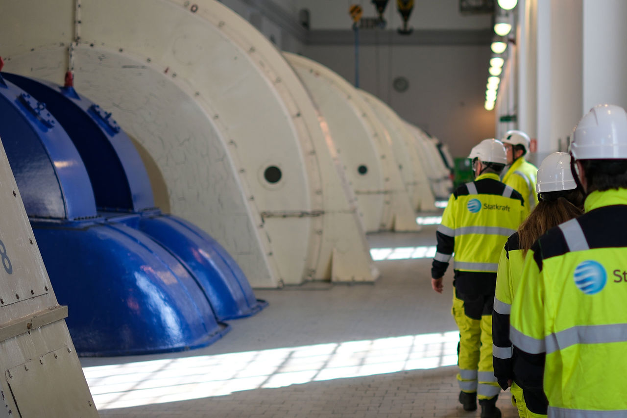 Ansatte går langs trubinene i et vannkraftverk